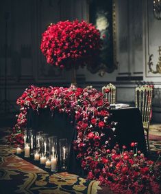 flowers and candles are arranged on the floor in front of an ornate table cloth with chairs