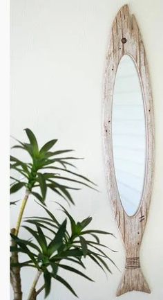 a wooden mirror hanging on the wall next to a potted plant in front of it