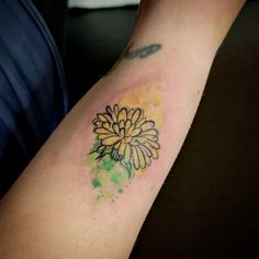 a yellow and green flower tattoo on the arm