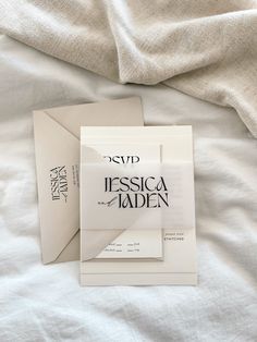 two folded cards sitting on top of a bed next to an envelope with the word, essica nadden