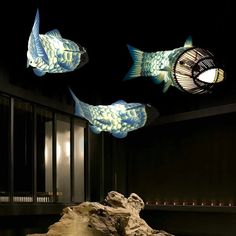 three fish that are floating in the air above some rocks and water with lights on them