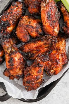 grilled chicken wings with celery on the side in a black tray, ready to be eaten