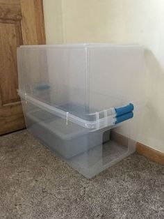 two plastic storage bins on the floor next to a door with blue handles and lids