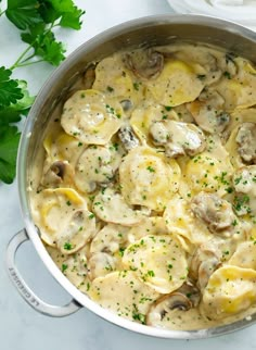 a pot filled with pasta and mushrooms covered in sauce on top of a white counter