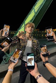 a group of people holding up cell phones with pictures of tigers on them