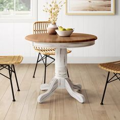 a white table with two chairs and a bowl of fruit on top of the table