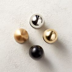 three metallic and black knobs on a white wall