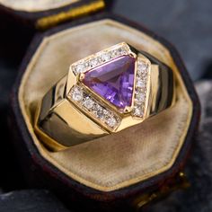 a gold ring with an amethyst purple stone surrounded by white and yellow diamonds