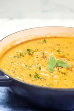 a close up of a bowl of soup on a blue cloth with a spoon in it