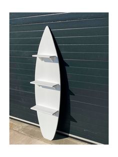 a white surfboard shaped shelf next to a garage door