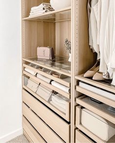 an organized closet with clothes and handbags on the shelves, all in light wood