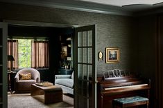 a living room filled with furniture and a piano in front of a window next to a chair