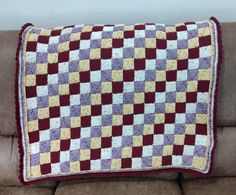 a crocheted pillow sitting on top of a couch next to a brown sofa