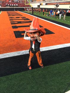 a woman dressed in an orange and black outfit is standing on the field with her hands behind her head