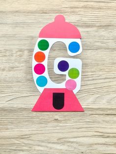 the letter g is made out of paper and has colorful dots on top of it