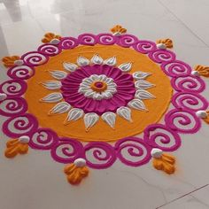 an orange and pink circular rug with white flowers on the floor in front of it