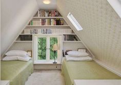 two beds in a small room under a slanted ceiling with books on the shelves