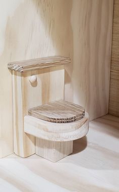 a wooden stool sitting on top of a hard wood floor next to a white wall