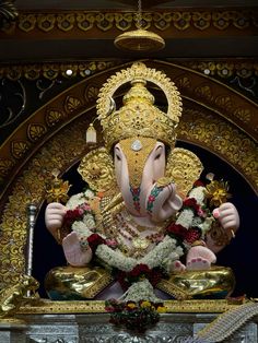 an elephant statue sitting on top of a table in front of a wall with gold decorations