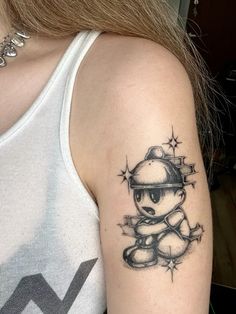 a woman with a tattoo on her arm has a small teddy bear wearing a helmet