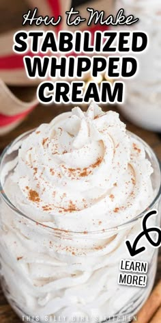 a glass bowl filled with whipped cream on top of a wooden table next to cinnamon sticks