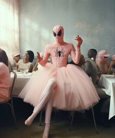 a person in a spiderman costume sitting at a table with people seated around it