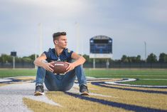 a man sitting on the ground with a football in his hand and looking at the camera