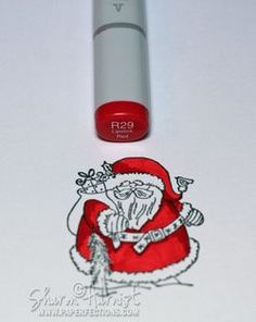 a santa clause sticker next to a red lip balm bottle on a white surface