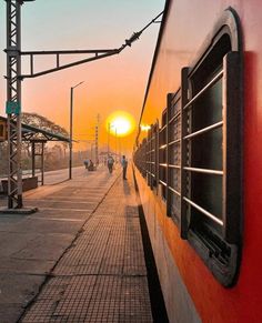 the sun is setting over an empty train station with people walking on the side walk