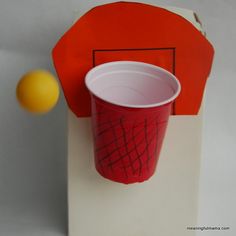 a red and white cup sitting on top of a counter next to an orange ball