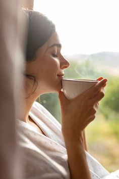 a woman drinking out of a coffee cup