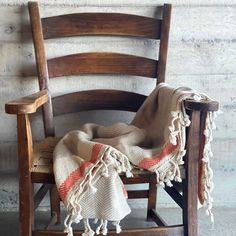 an old chair with a blanket on it and a wooden rocking chair in the background