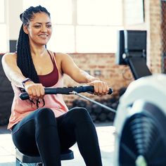 a woman is smiling as she sits on a stationary exercise bike in a gym area