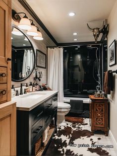 a bathroom with black and white decor and cow hide rug