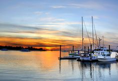 several boats are docked in the water at sunset