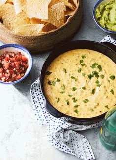 several bowls of guacamole, chips and salsa on a table with napkins