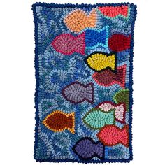 a colorful patchwork wall hanging with hearts and fish on blue ground, in front of a white background