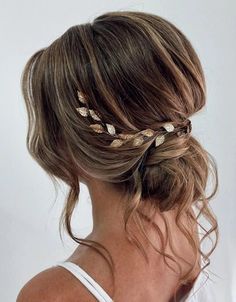 a woman wearing a white tank top and gold leaf hair combs in her hair