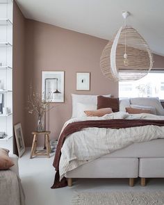 a white bed sitting under a window next to a wooden shelf filled with pictures and pillows