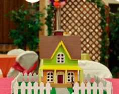 a small toy house sitting on top of a table next to a white picket fence