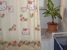 a shower curtain with hello kitty designs on it and a potted plant in the corner