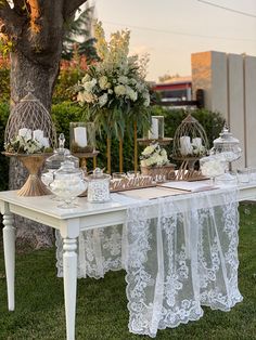 the table is set up with white flowers and birdcages on it for an outdoor wedding reception