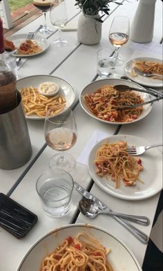 several plates of food on a table with wine glasses and utensils in front of them