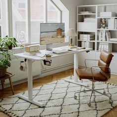 a home office with a desk, chair and bookshelf in the corner near windows