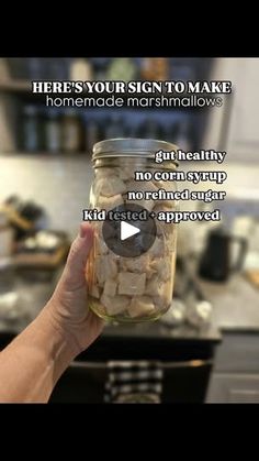 someone is holding up a jar full of marshmallows in the middle of a kitchen