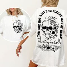 a woman wearing a white t - shirt with a skull and flowers on it