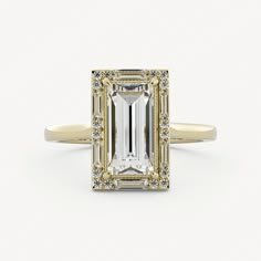 an emerald cut diamond ring with diamonds around the band and side stones in yellow gold