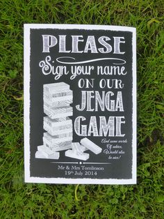 a sign on the grass that says please sign your name on our jenga game