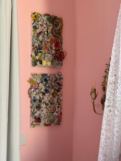 a bathroom with pink walls and two pictures hanging on the wall next to a toilet