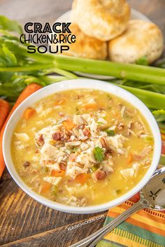 a bowl of chicken and rice soup with carrots, celery and bread in the background